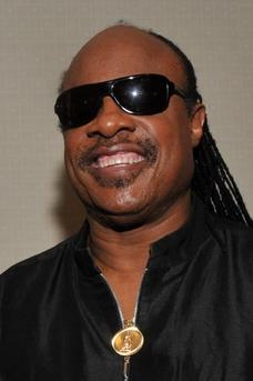 A close up of Stevie Wonder wearing black tinted glasses and a black shirt.